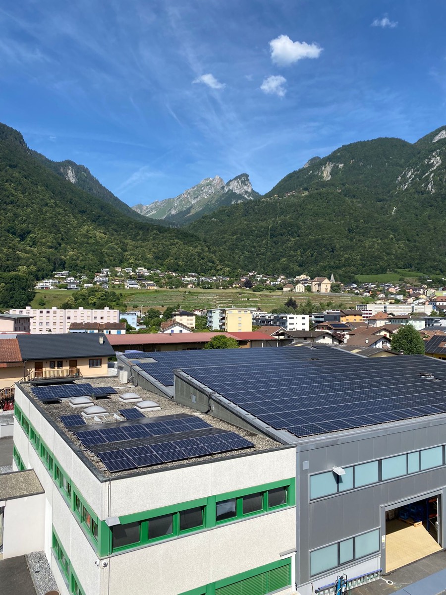 Toiture d'un bâtiment commercial couverte de panneaux, village et montagnes autour