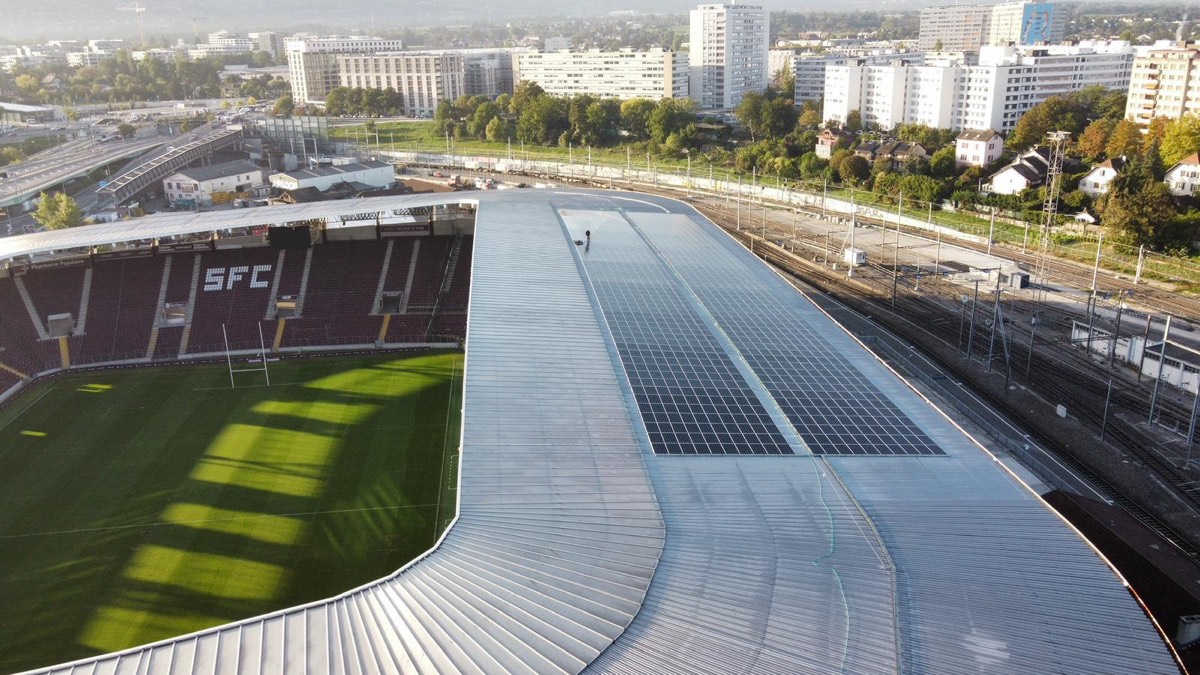 Toiture inclinée du stade vue de près, robot de nettoyage en action sur les panneaux