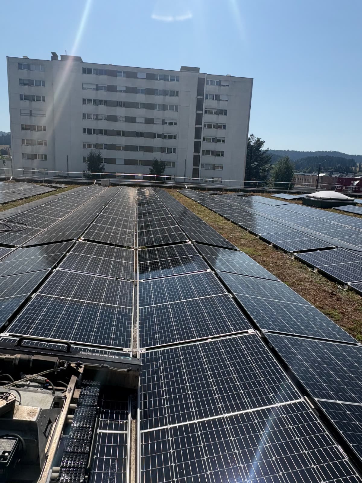 Le robot de nettoyage en action entre deux rangées de modules sur la toiture du Migros Les Eplatures