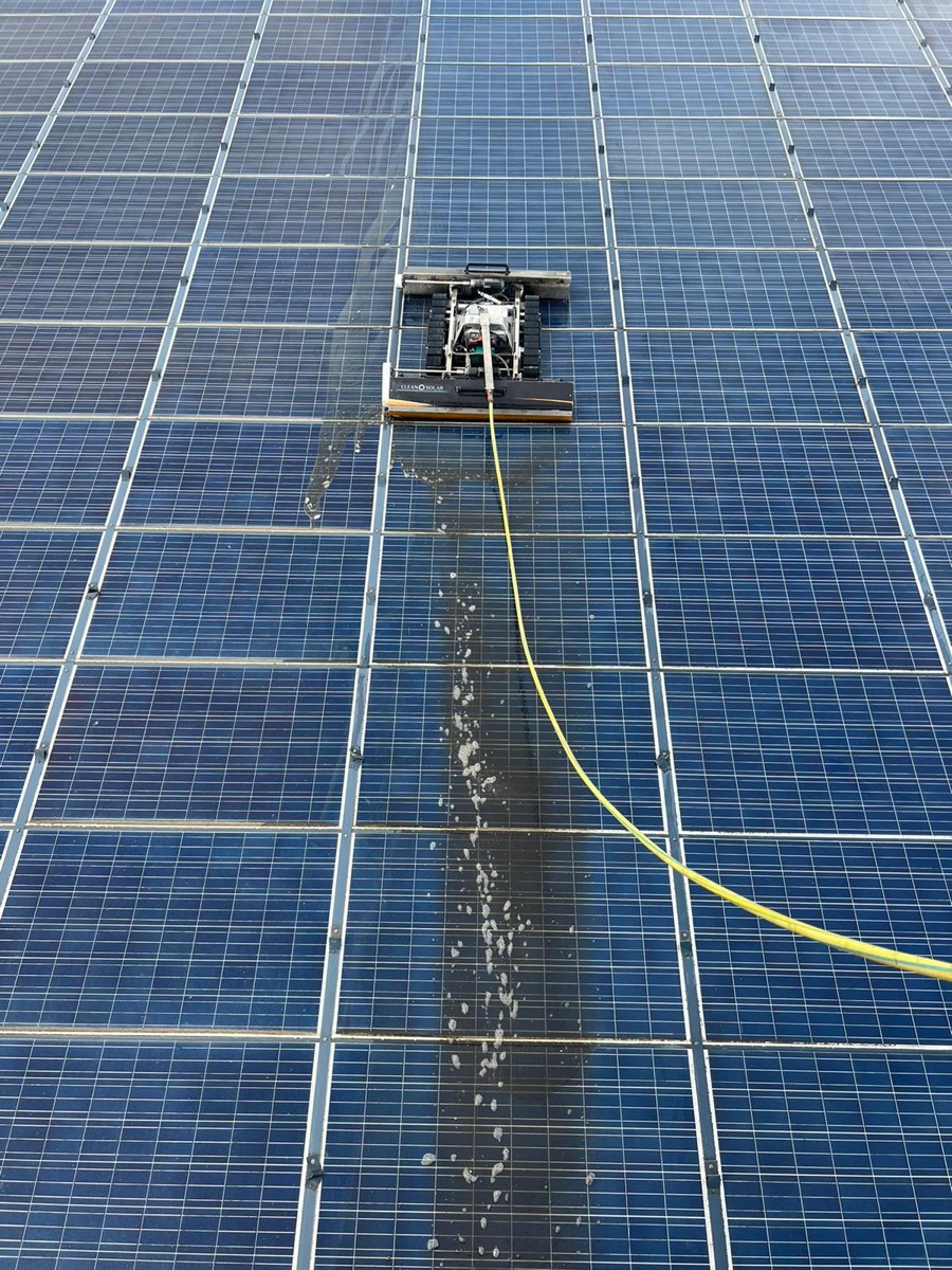 Robot en train de rincer une rangée de panneaux à l'eau déminéralisée