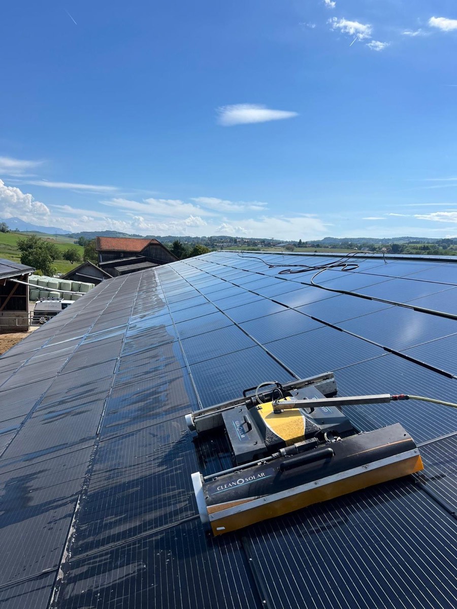 Robot Cleanosolar sur le rampant d'un hangar agricole, laissant derrière lui une bande de panneaux nettoyés